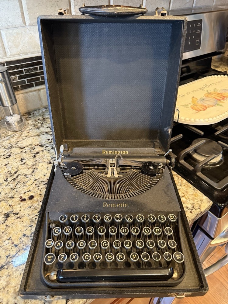A vintage black Remington Rem-ette portable typewriter in its case.